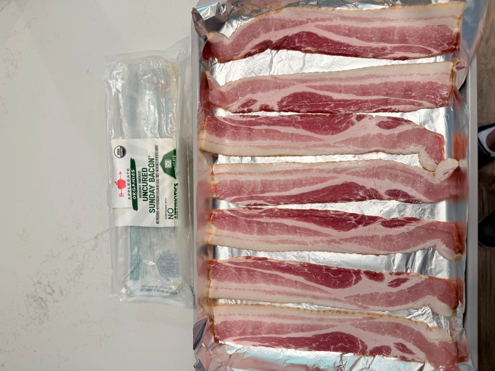 Bacon strips laid out on a baking sheet ready for the oven